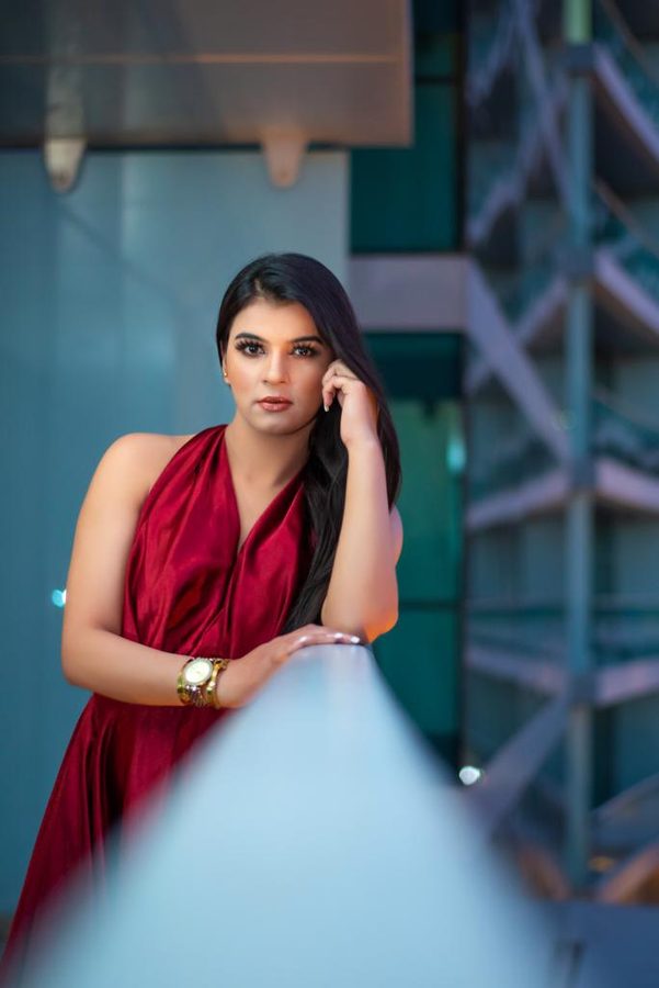 Mehak Shalle leaning on a railing in a red satin top